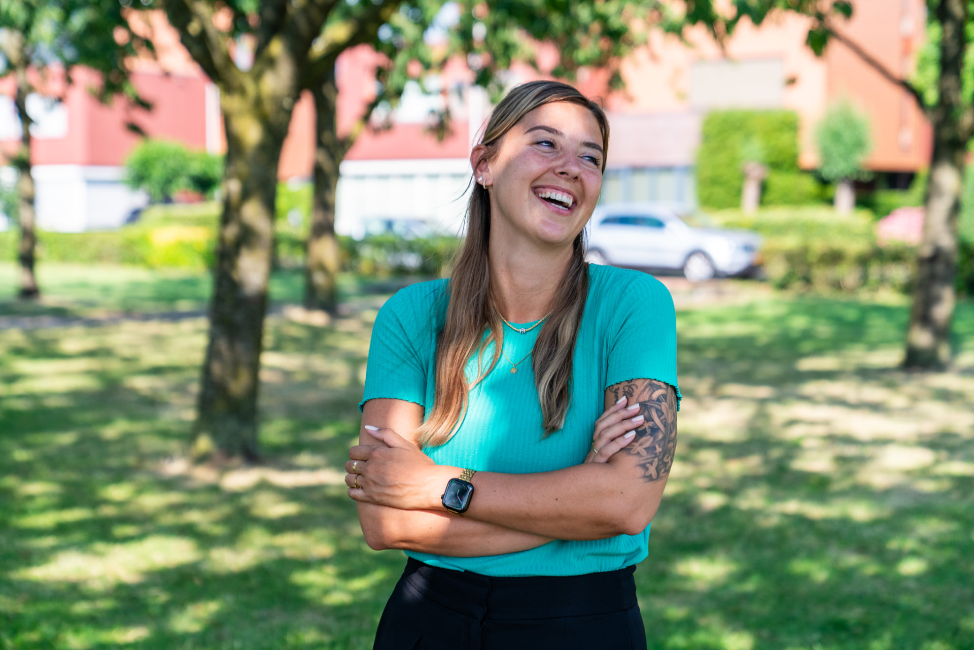 Een jonge vrouw lacht buiten in een park
