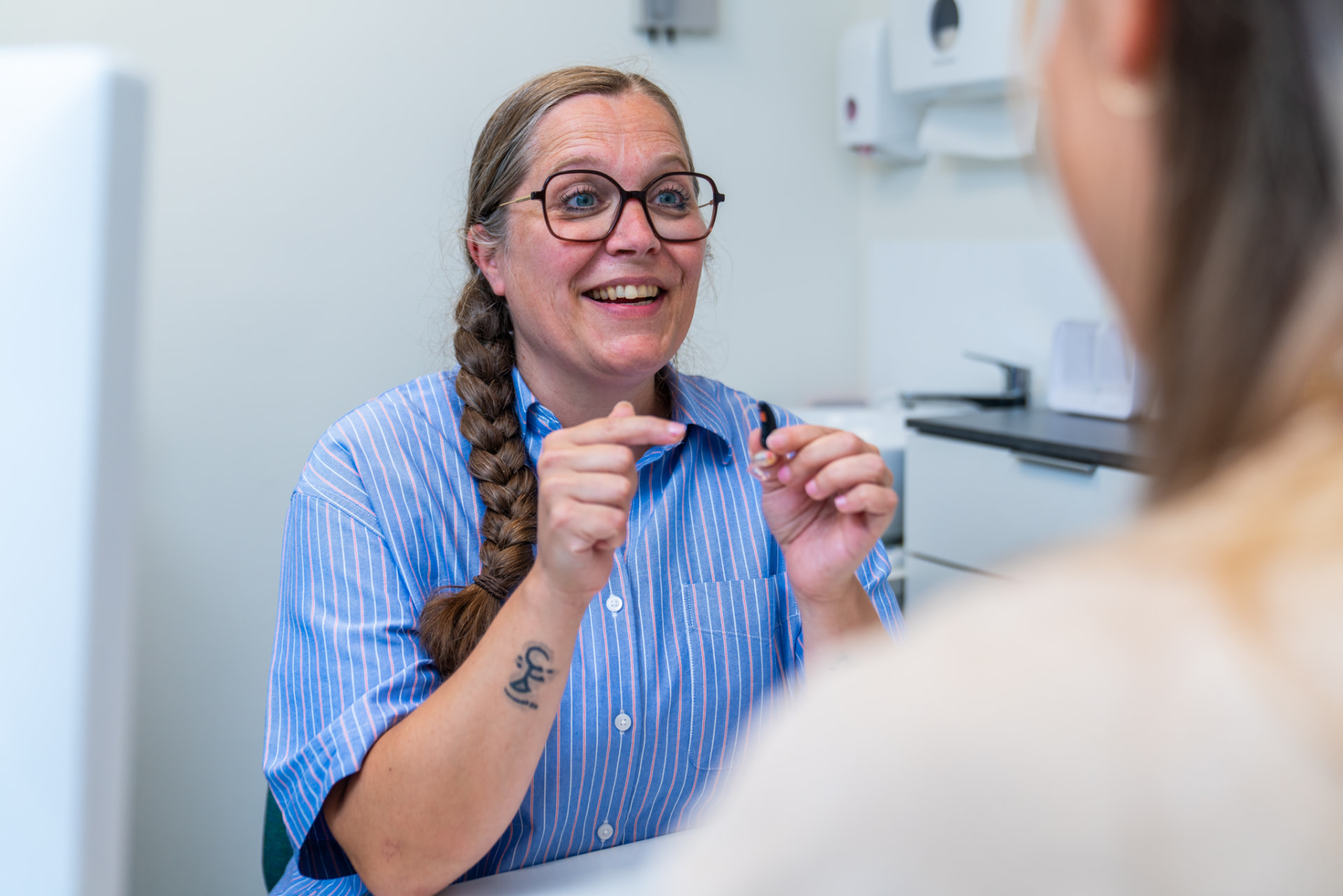 Een audicien legt een client uit hoe een gehoorapparaat werkt